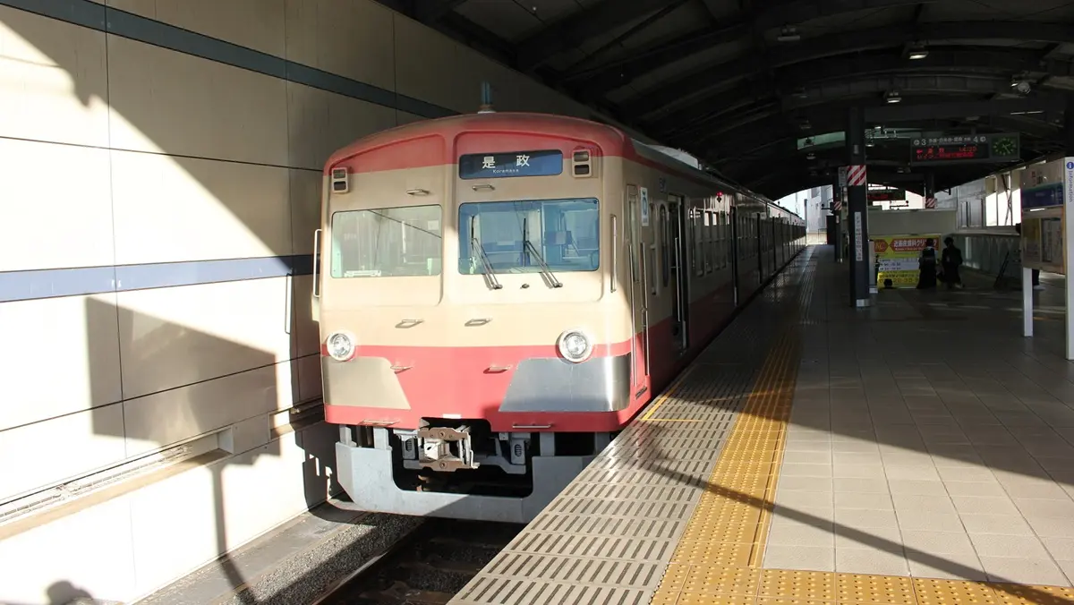 A red Seibu Tamagawa Line 101 series train parked at Musashi-Sakai Station